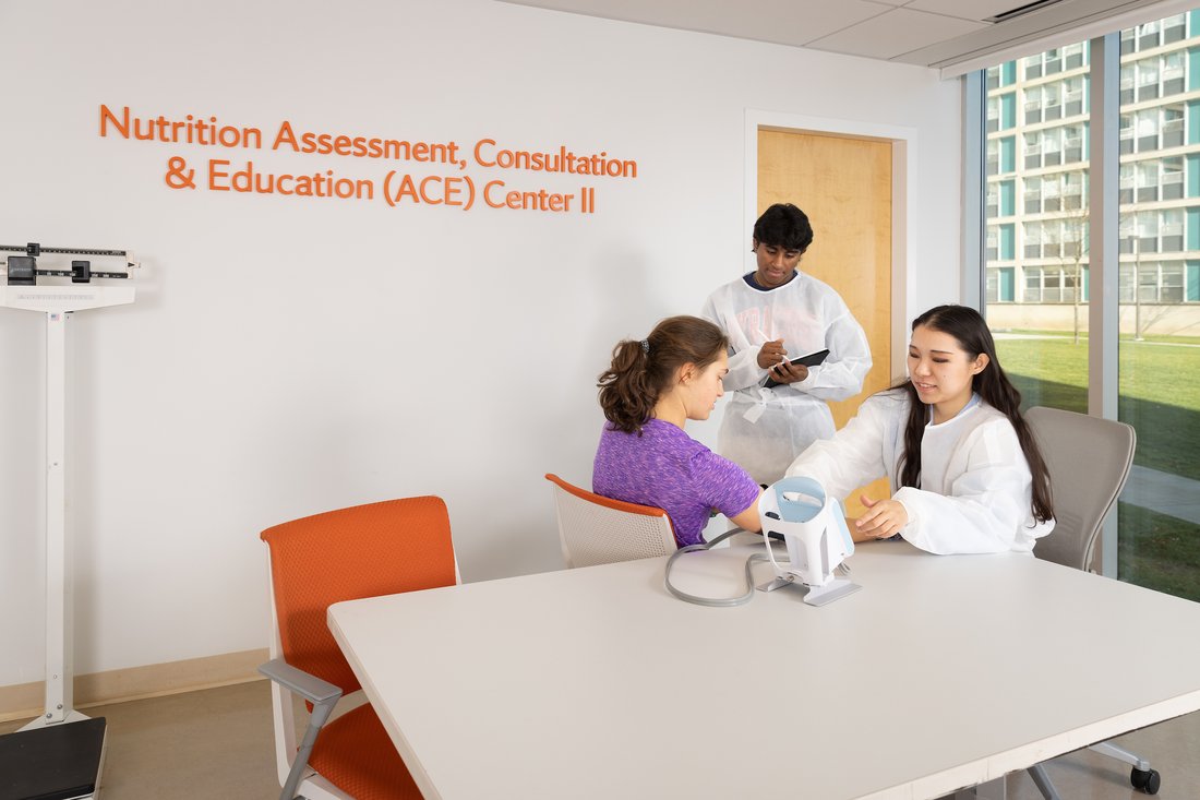 Two students take nutrition measurements with a subject in ACE Center II