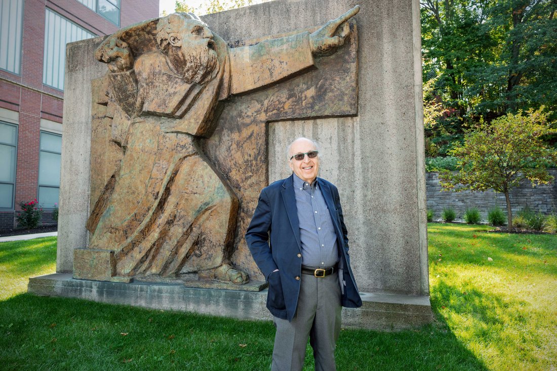 Man standing in front of a sculpture of Moses