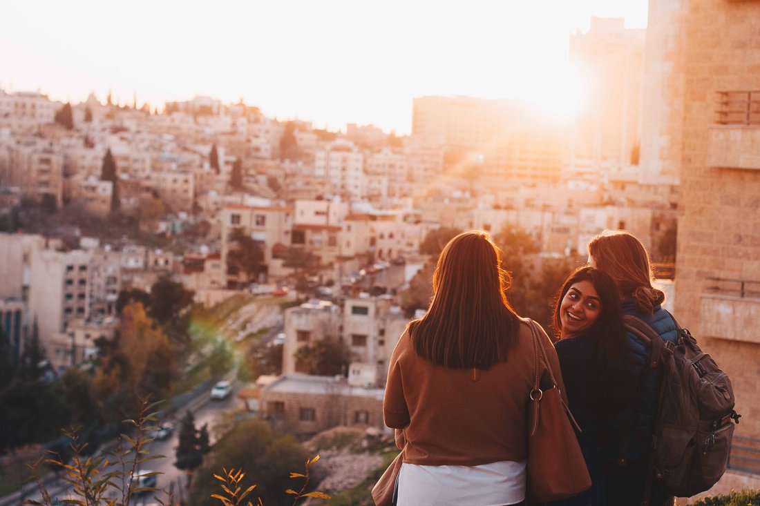 Three people looking down at a city at sunset