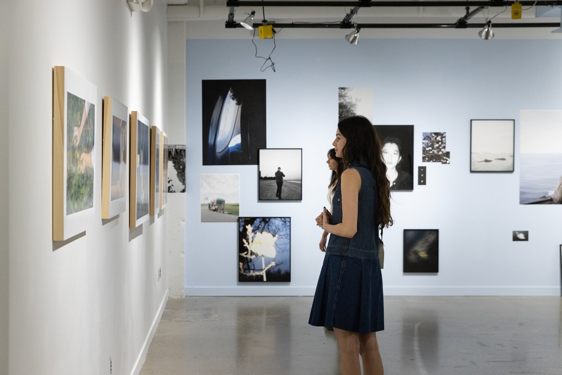 A person looks at framed photographs on a wall in a gallery