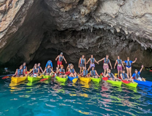 People in colorful canoes under a cliff
