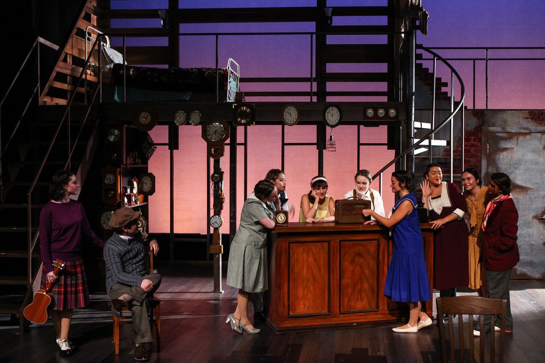 A group of actors in costume gather around a bar on stage in a scene from Failure: A Love Story