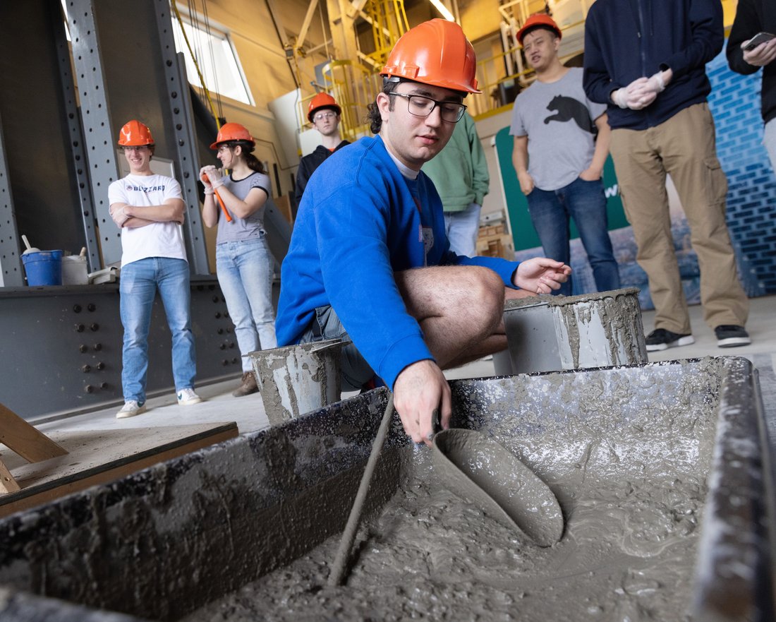 Civil Engineering student doing a concrete beam pour during class.