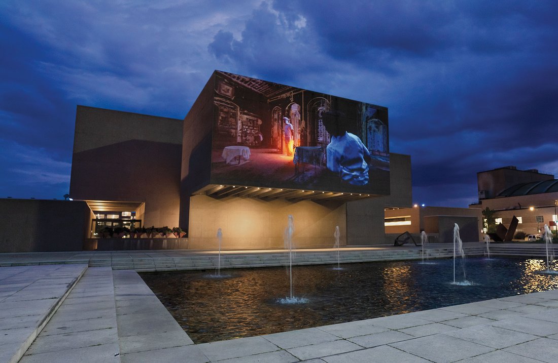 Exterior of a modern building with an image projected on it in the evening.