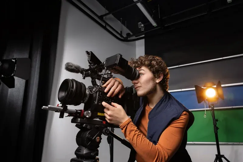 Person looking into a video camera in a recording studio.